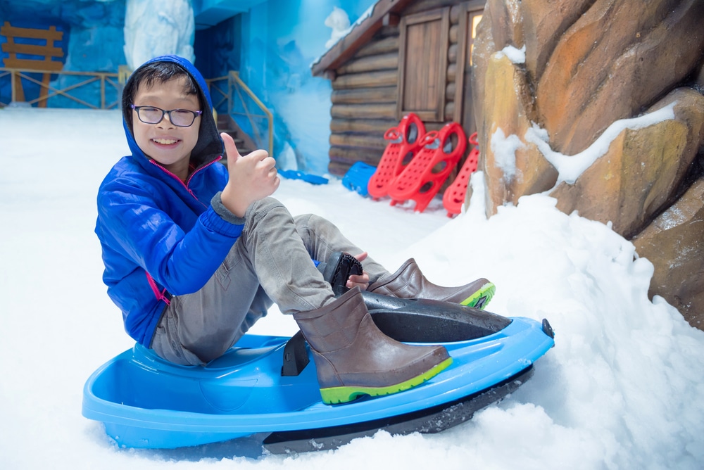 Boy Riding Sleigh Indoor Snow Land